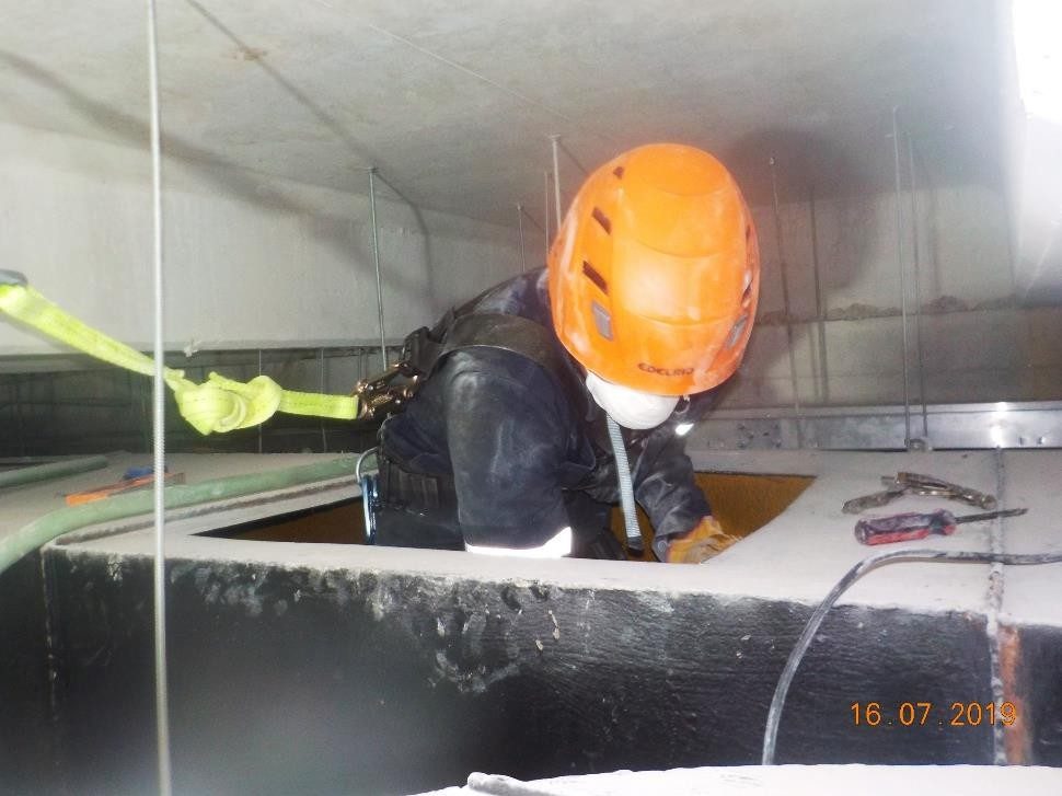 Técnico de Control Biológico con casco y arnés limpiando un ducto de extracción