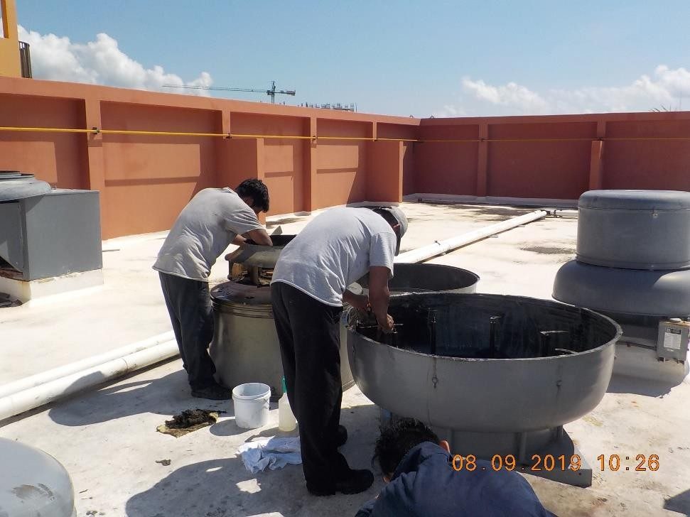 Dos técnicos limpiando extractores en una azotea