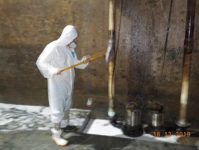 Técnico con traje de protección limpiando tuberías dentro de un cárcamo